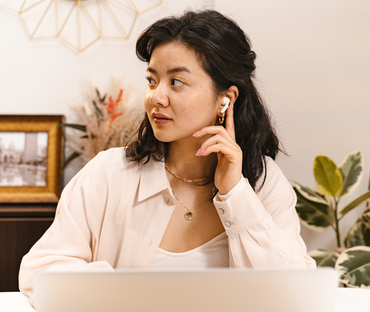 Woman frustrated with low AirPods volume, checking phone for solutions.